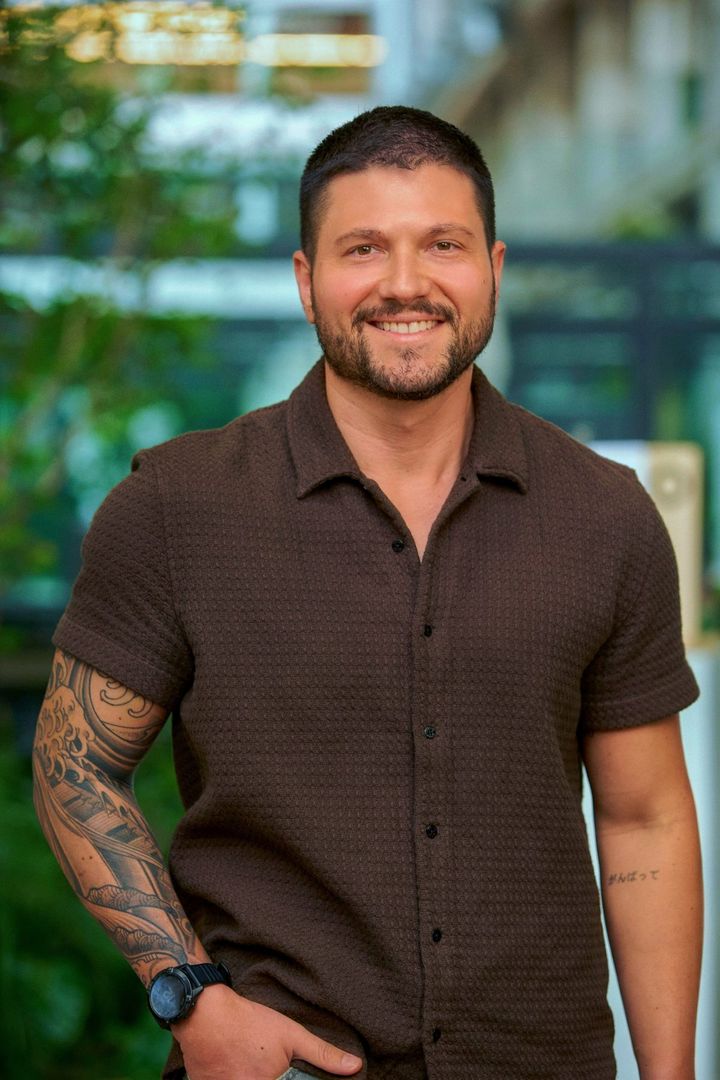 Retrato de Ricardo Caires sorrindo, de camisa marrom